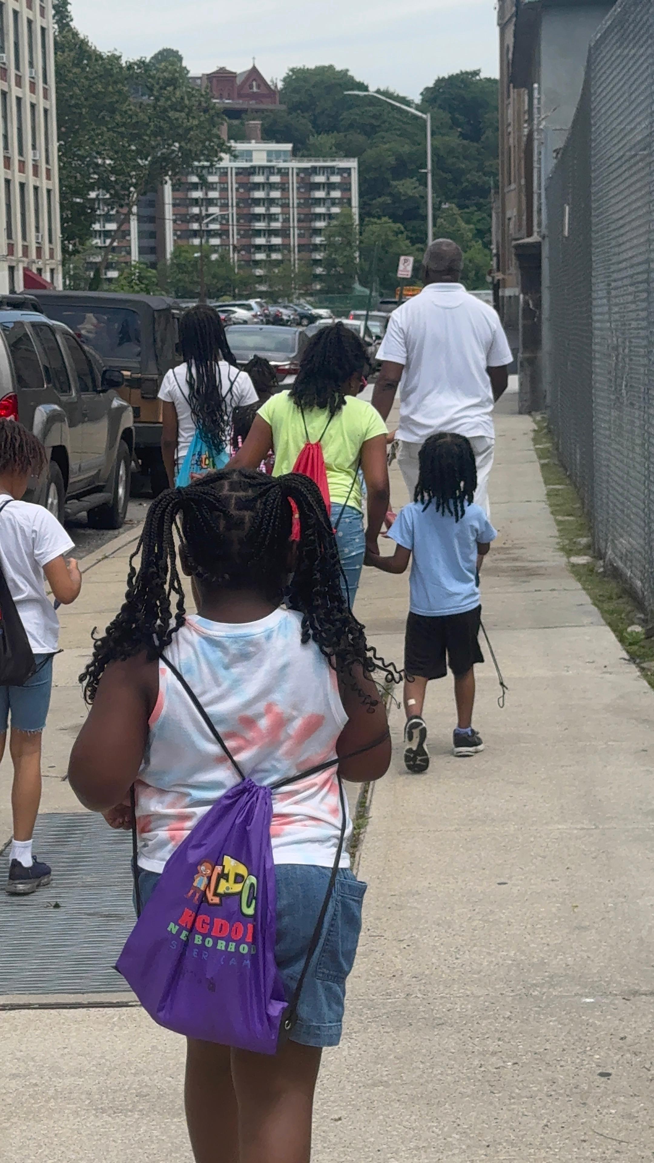 Campers head out on a neighborhood walk with their KDC backpacks